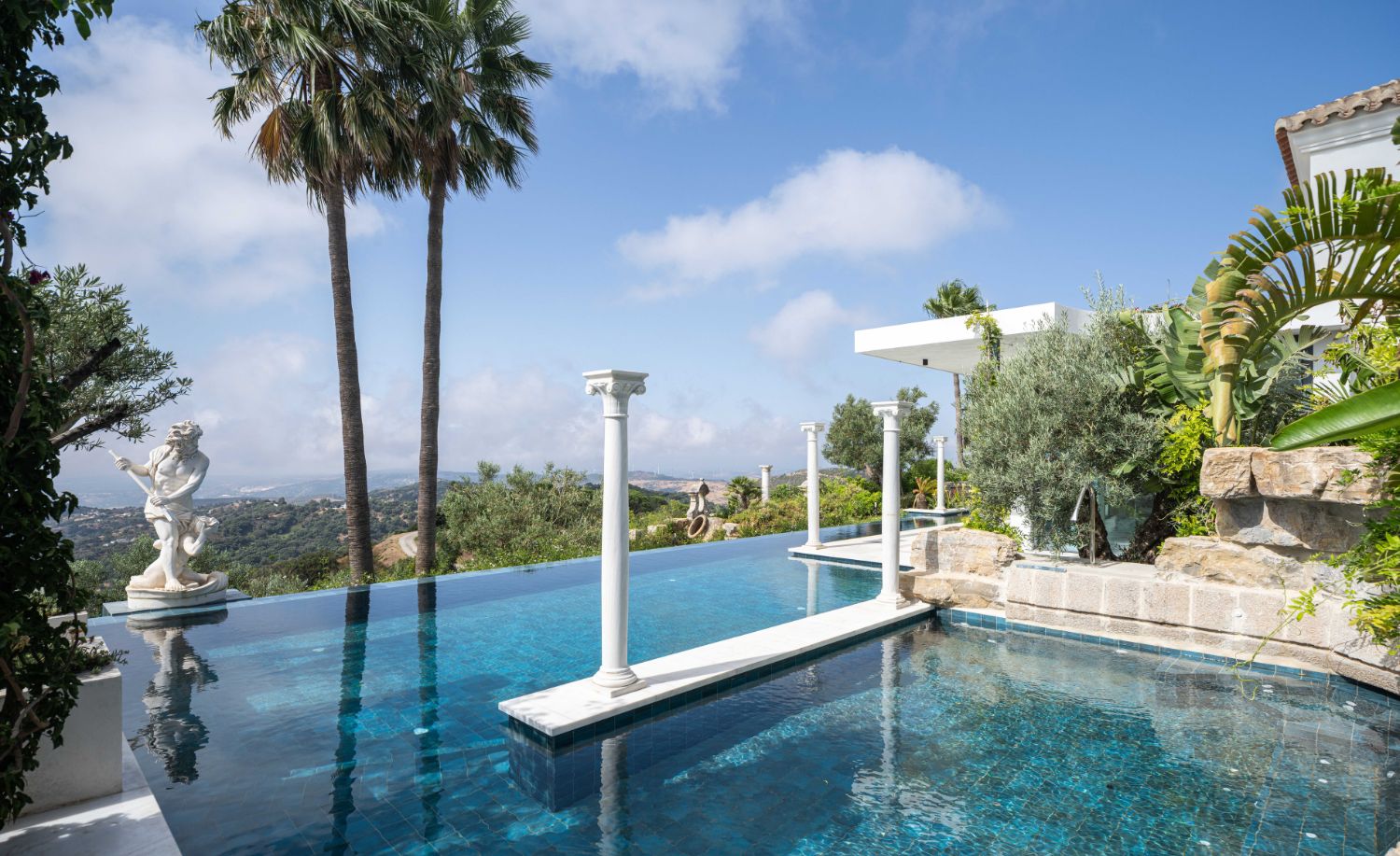 Piscina infinita con columnas y escultura clásica en la Villa Heritage