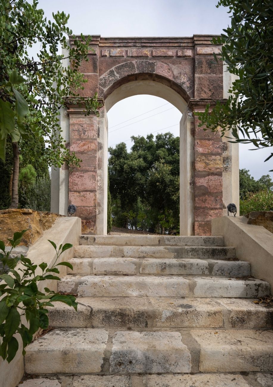 Arco de piedra sobre una escalinata en los jardines de la Villa Heritage