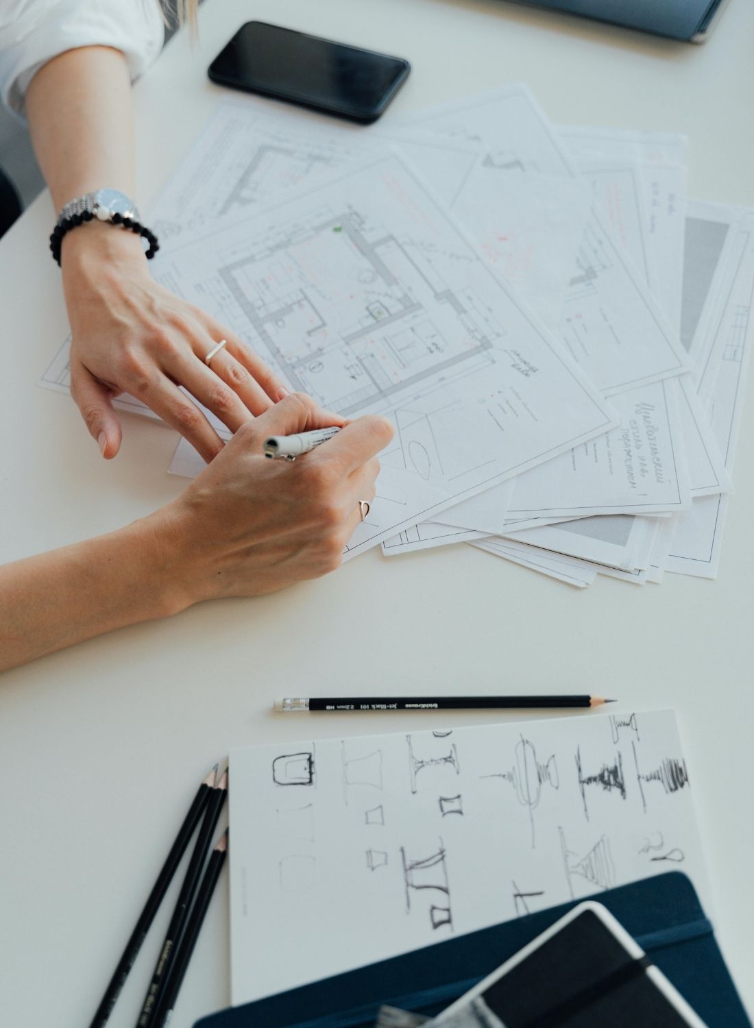 Manos dibujando y revisando planos de obra sobre una mesa de trabajo