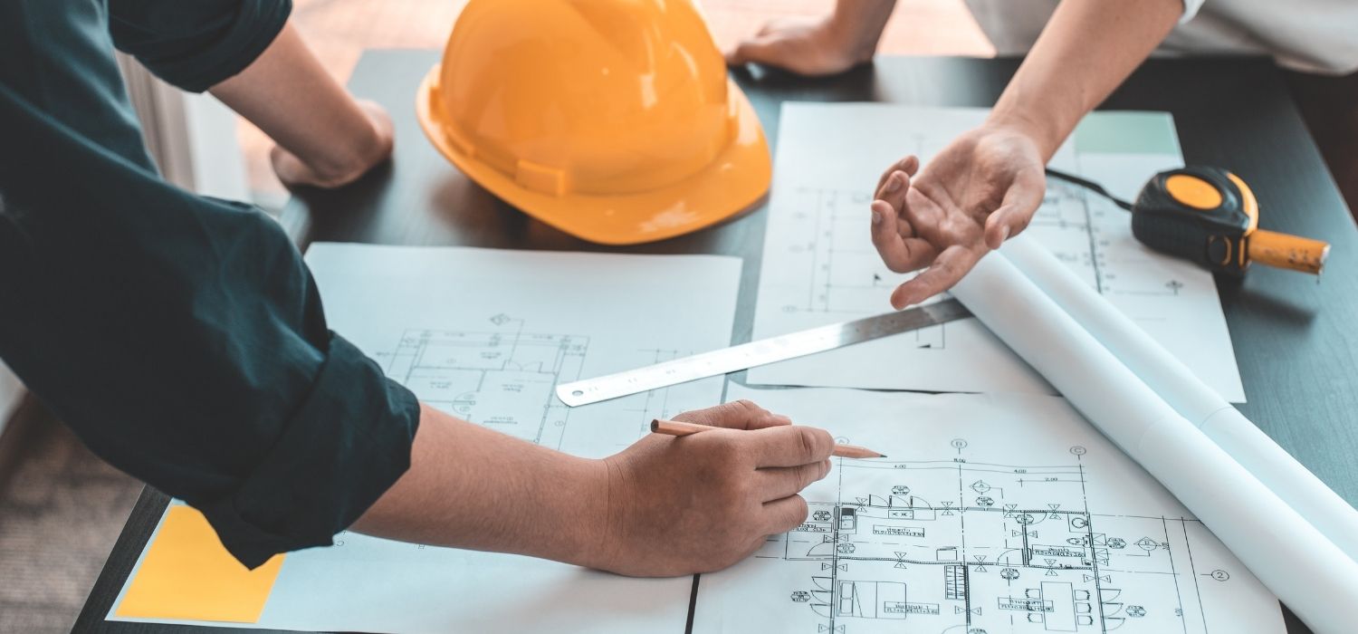Casco de obra, cinta métrica y planos durante la revisión de un proyecto de construcción