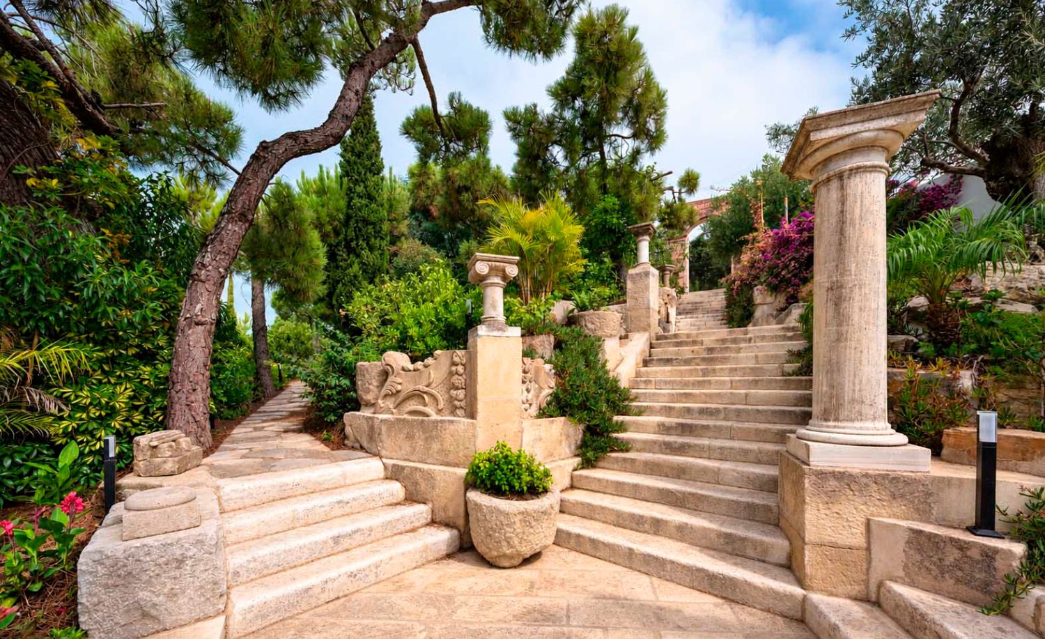 Escalinata de piedra con columna antigua rodeada de vegetación en la Villa Heritage