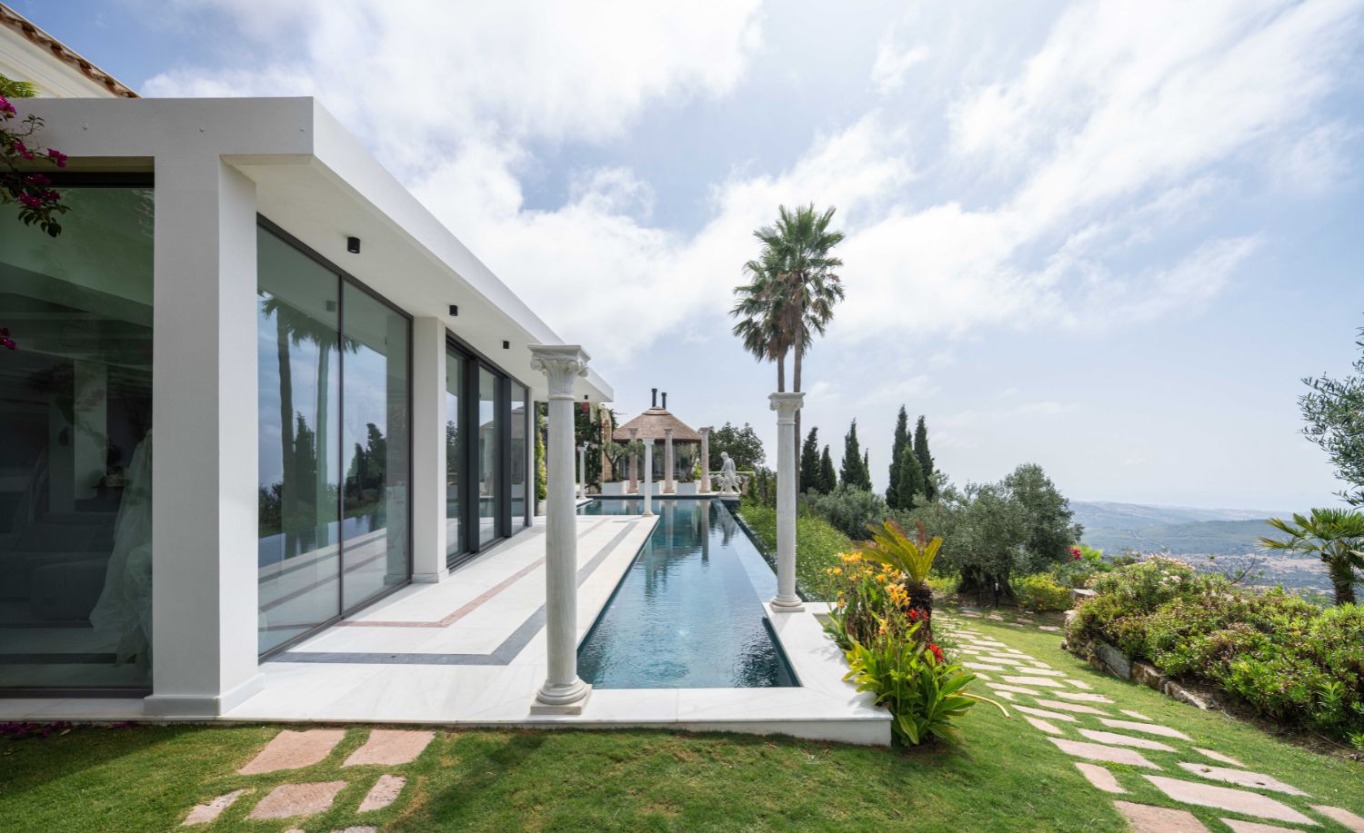 Fachada contemporánea blanca con grandes cristaleras junto a la piscina de la Villa Heritage