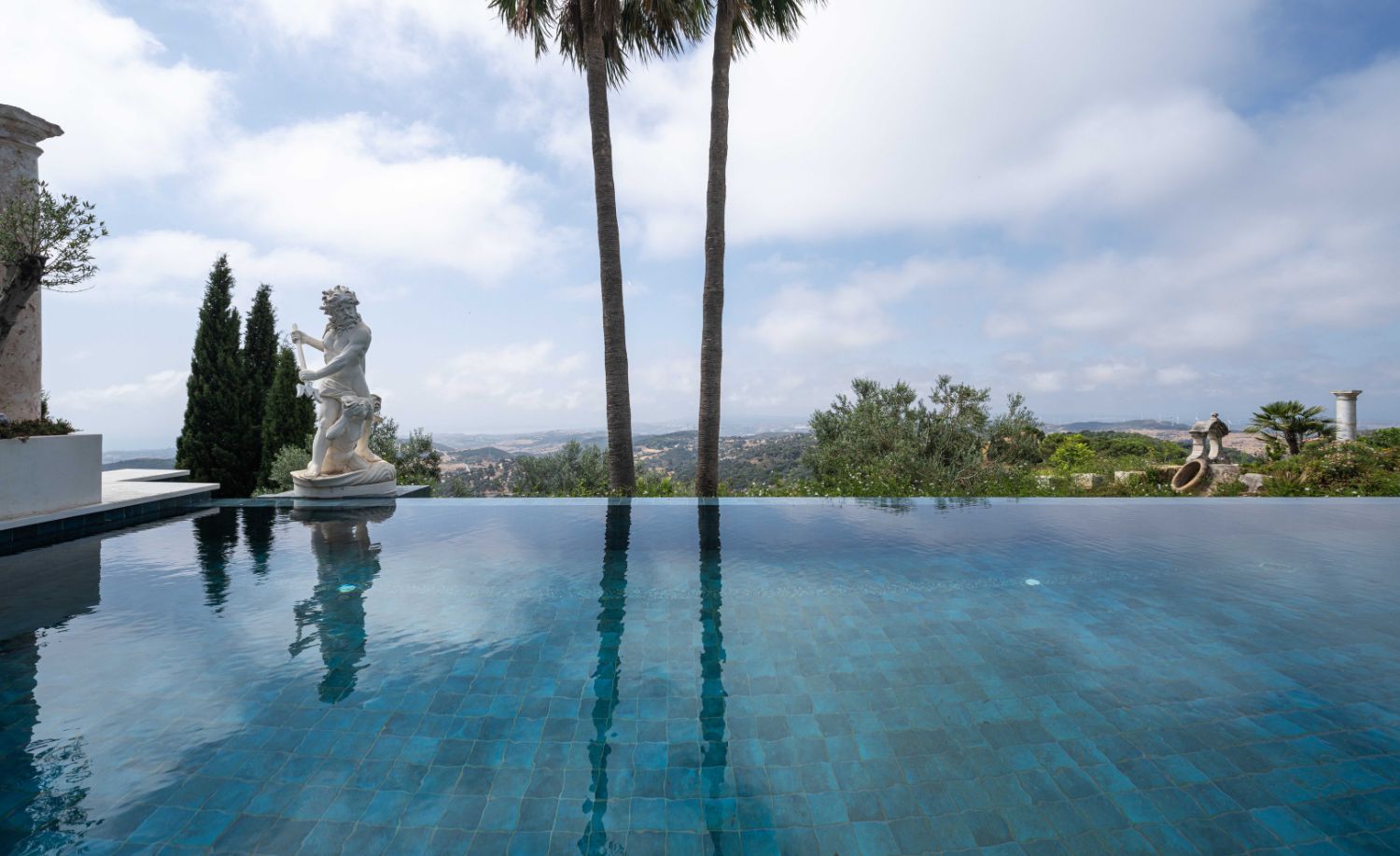 Piscina infinita con palmeras y vistas panorámicas al mar en la Villa Heritage