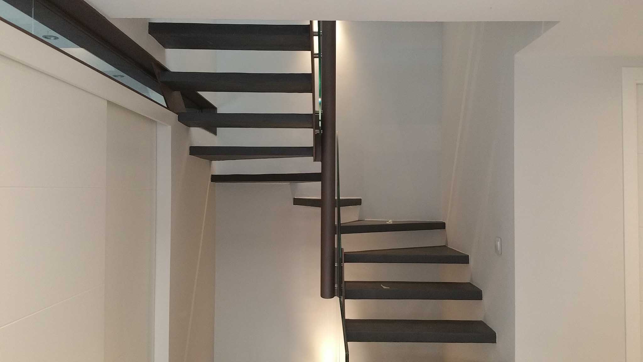 Escalera interior de peldaños oscuros volados en la vivienda contemporánea de Málaga