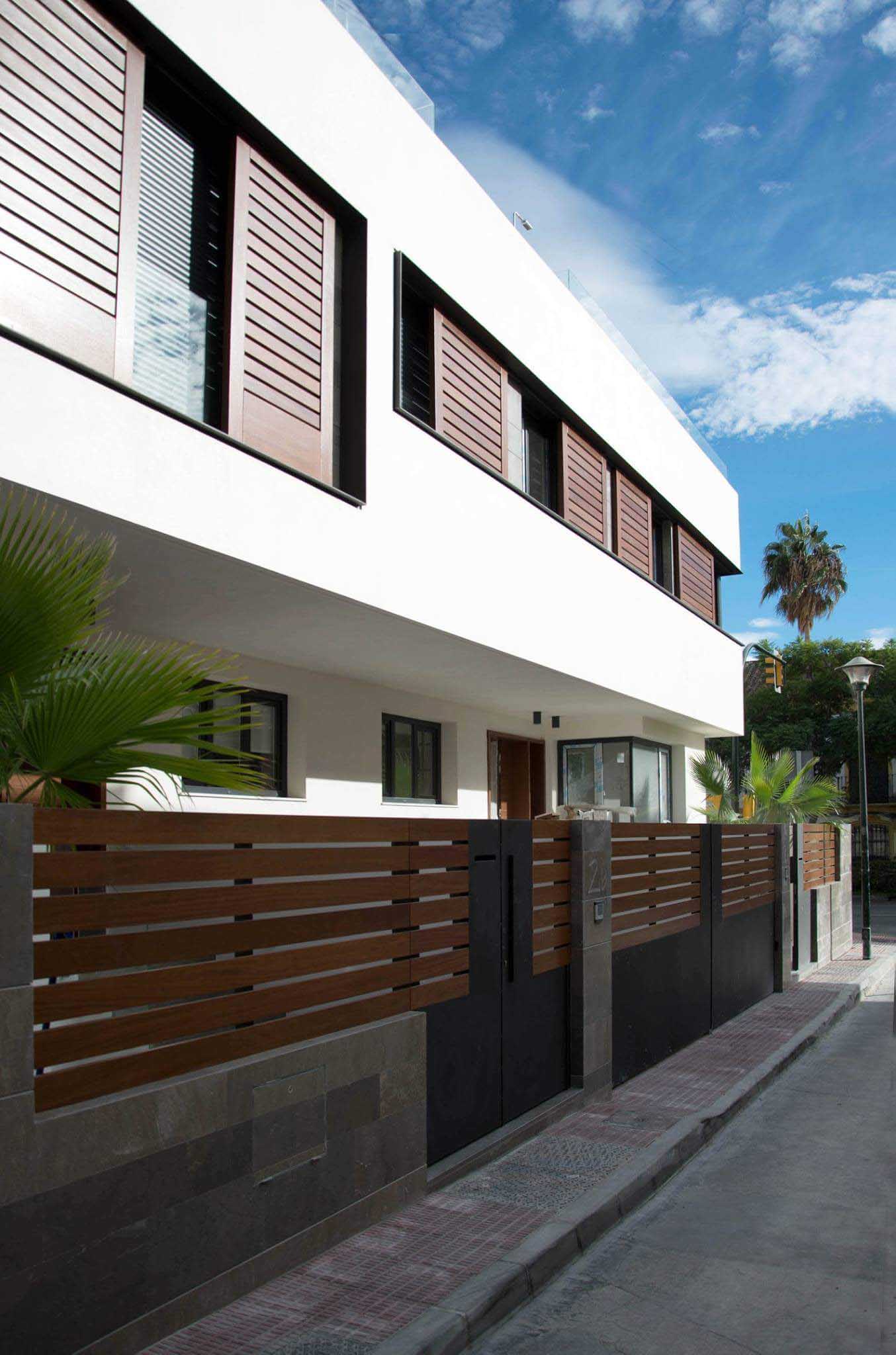 Valla de lamas de madera y fachada contemporánea en la calle de las viviendas pareadas de Málaga