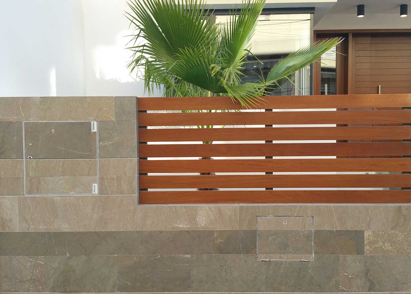 Muro de piedra natural con vallado de lamas de madera en las viviendas contemporáneas de Málaga