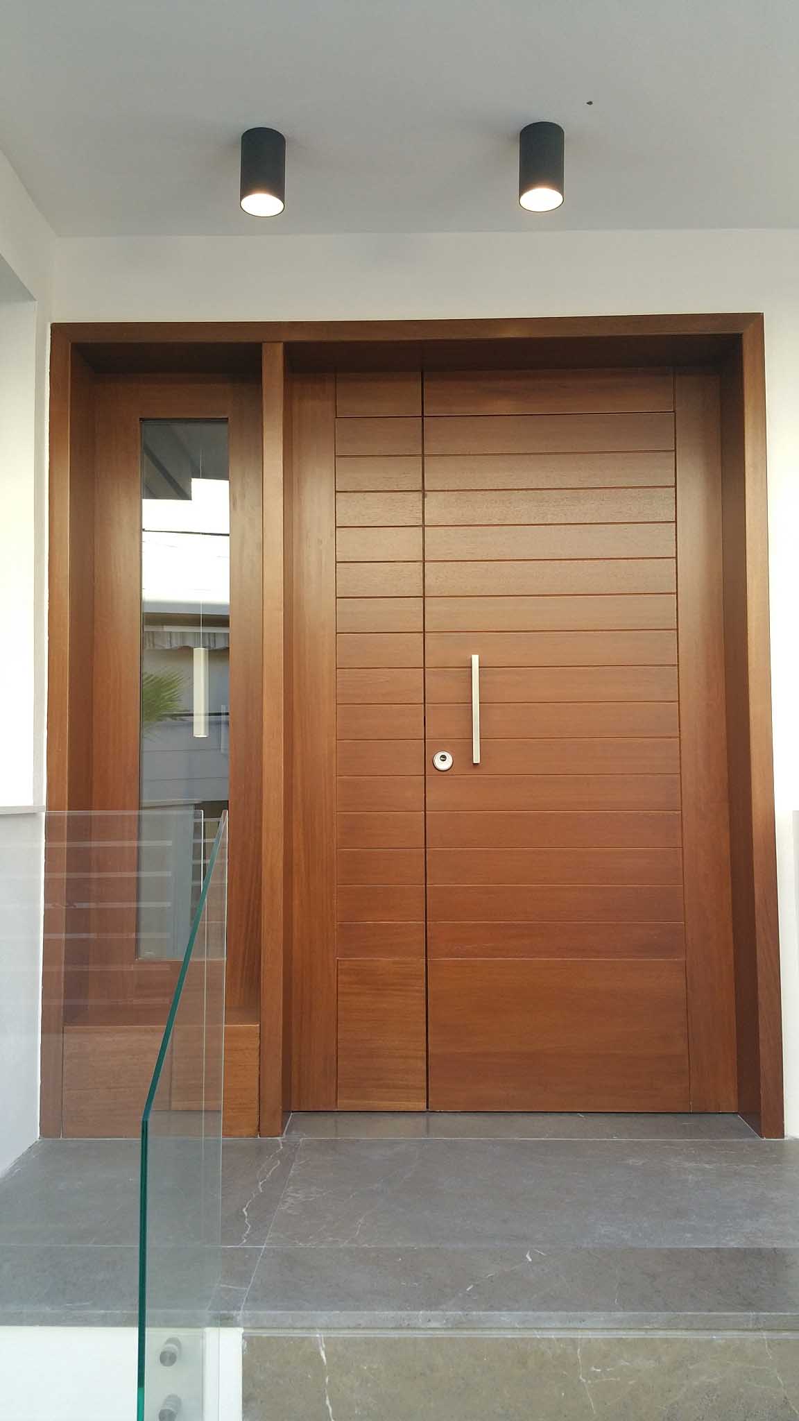 Puerta de entrada de madera de doble hoja con iluminación empotrada en la vivienda de Málaga