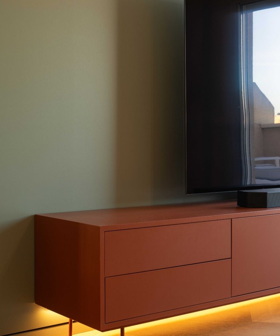 Mueble bajo naranja con retroiluminación junto al televisor en el salón reformado