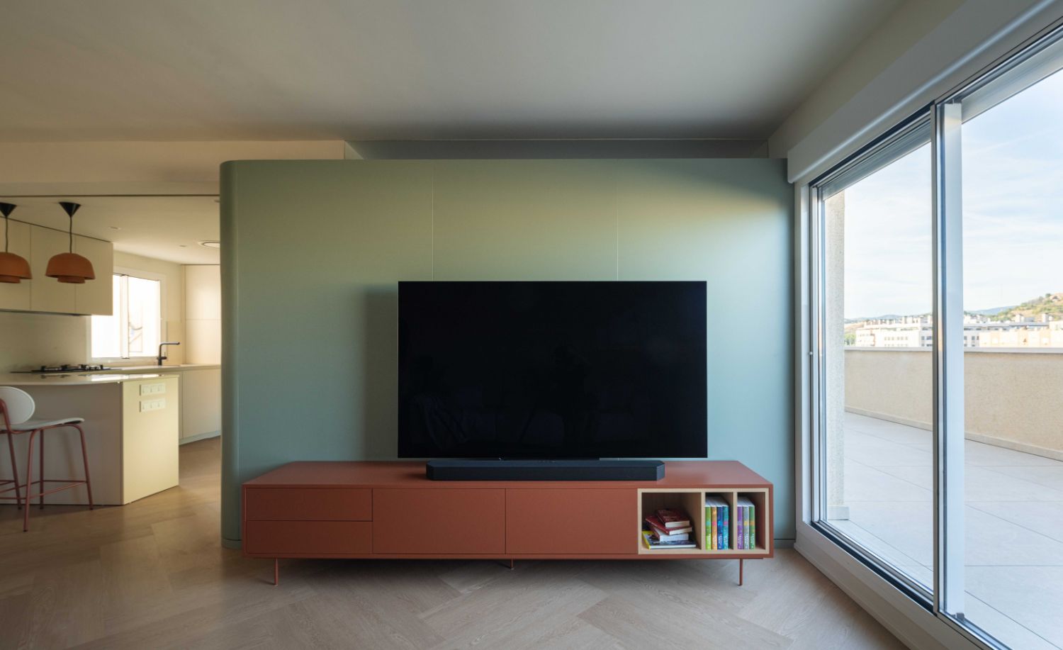 Salón con televisión, mueble naranja y gran ventanal tras la reforma integral