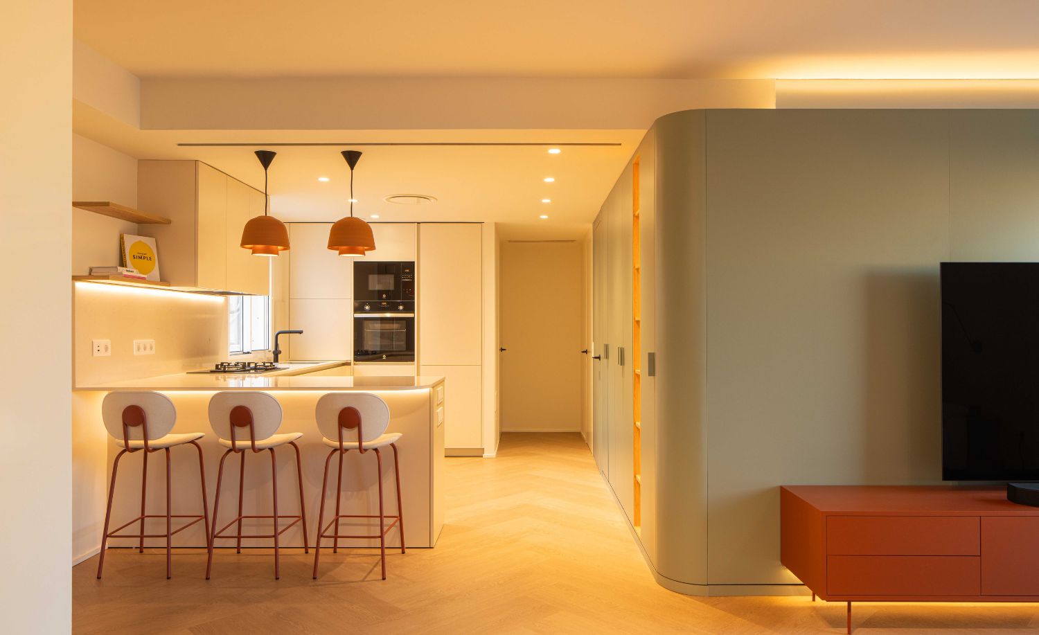 Cocina abierta con barra y taburetes junto al salón de la vivienda reformada