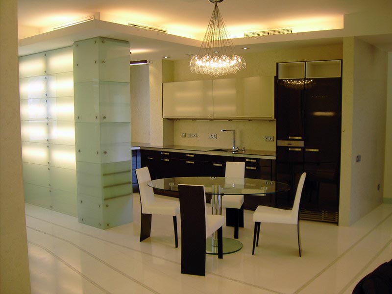 Cocina y comedor con revestimientos de vidrio e iluminación indirecta en la vivienda de Marbella