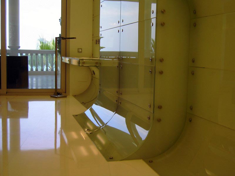 Revestimiento curvo de vidrio sobre suelo brillante junto a la terraza en la vivienda de Marbella