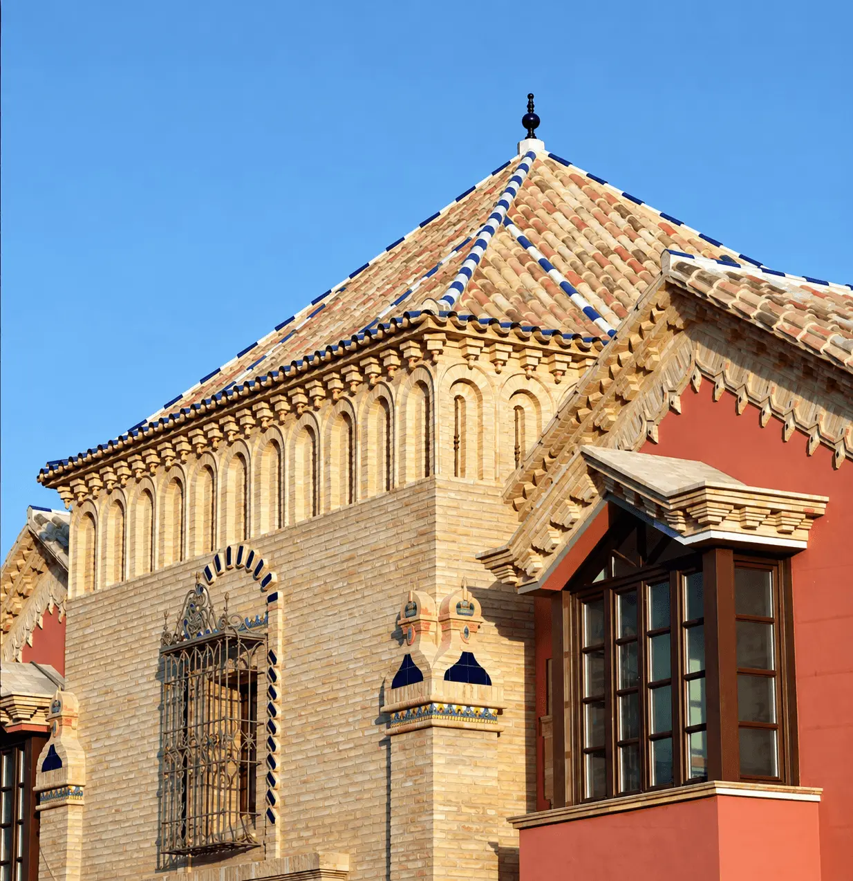 Torreón de ladrillo antiguo y teja cerámica con ventanas enrejadas en la villa de Marbella