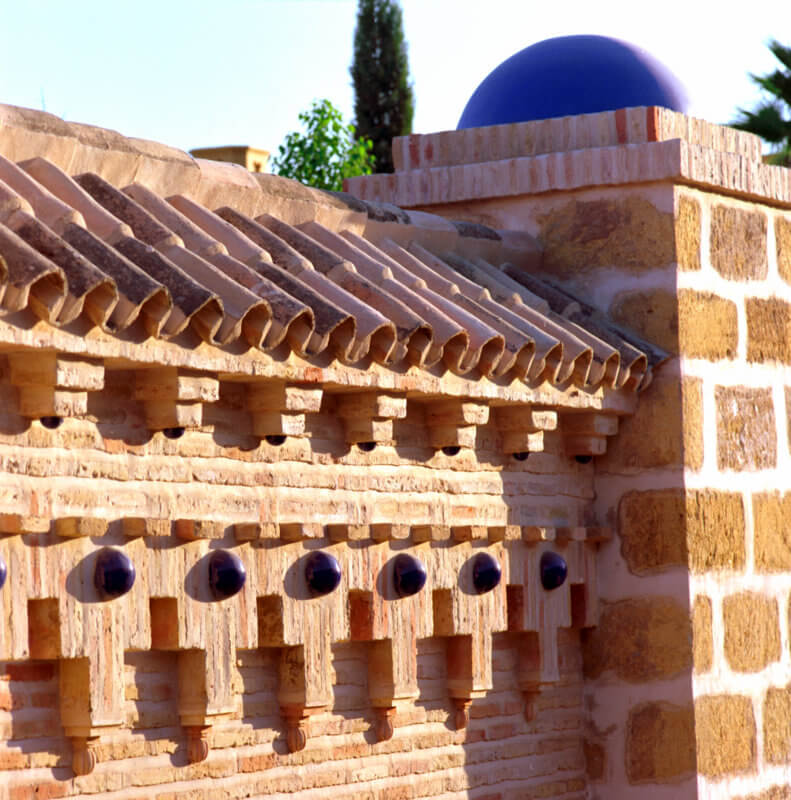Cubierta de teja cerámica y cúpula azul sobre muro de ladrillo artesanal en la villa de Marbella
