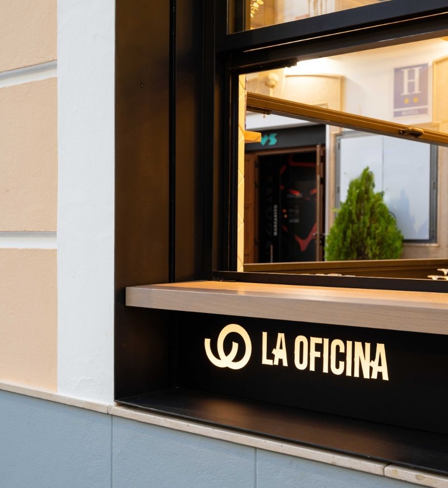 Rótulo luminoso La Oficina en la ventana exterior del local