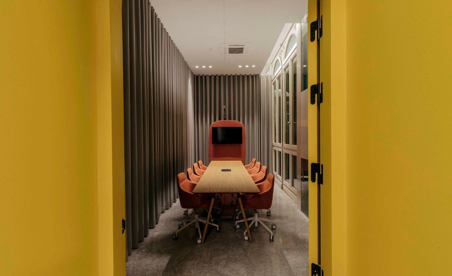 Sala de reuniones con paredes amarillas y mesa alargada en las oficinas de Uptodown