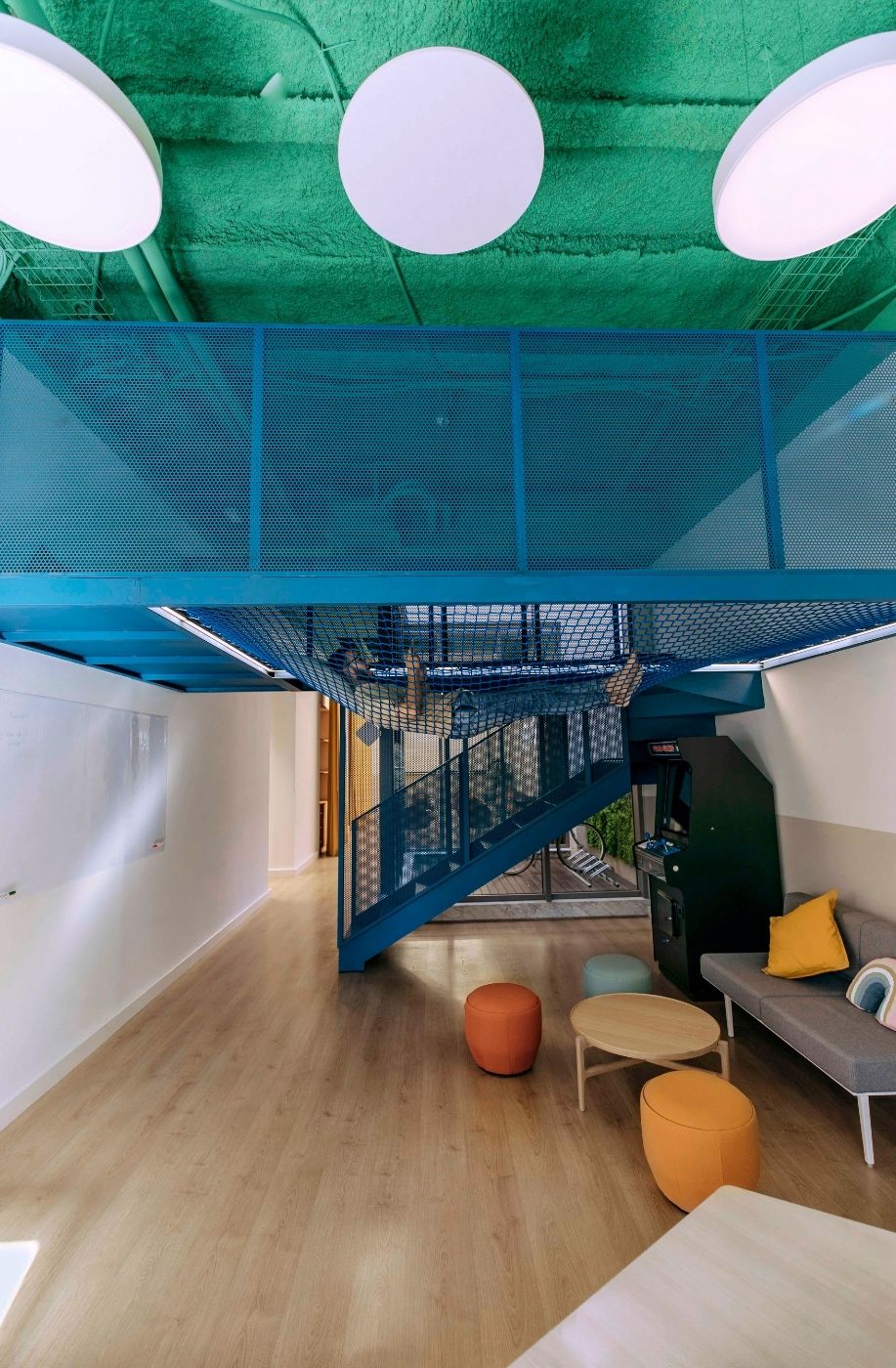 Zona de descanso con puffs naranjas y techo verde en las oficinas de Uptodown