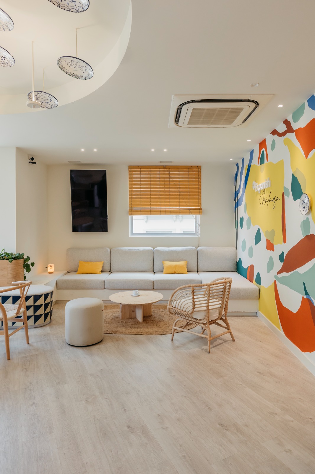 Zona de estar de la academia de idiomas con sofás, mesas bajas y mural colorido