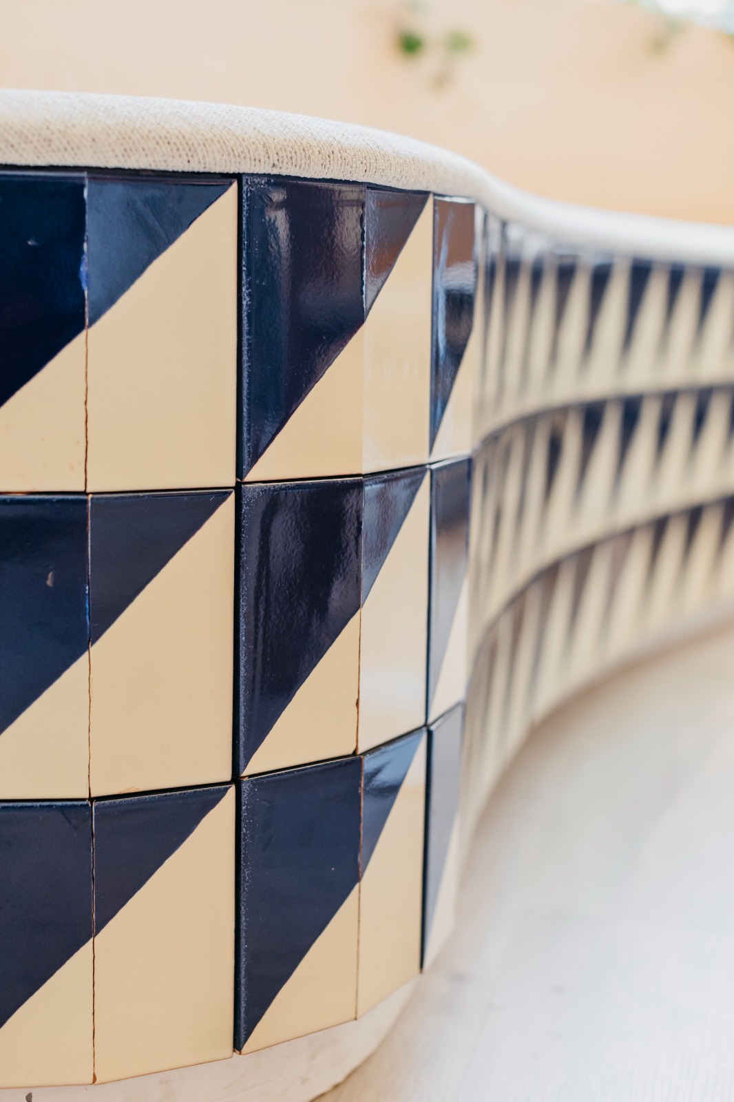 Detalle del banco curvo con azulejos geométricos azul marino y crema en la academia de idiomas
