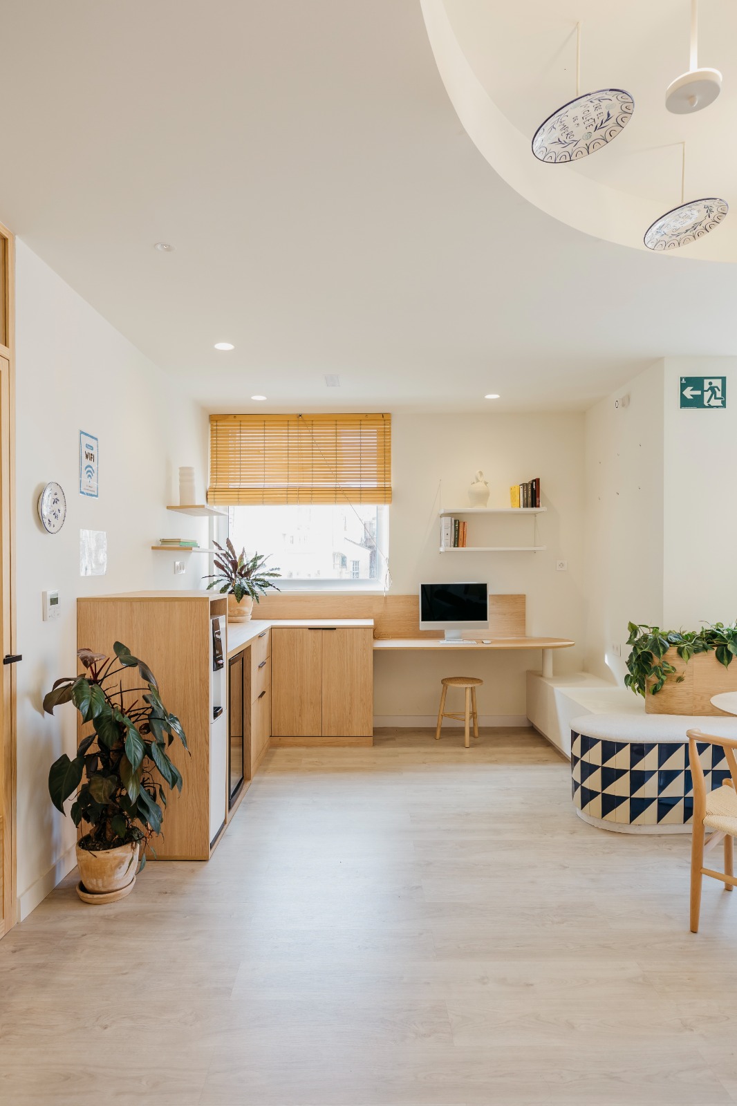 Sala luminosa con mobiliario de madera y plantas en la academia de idiomas