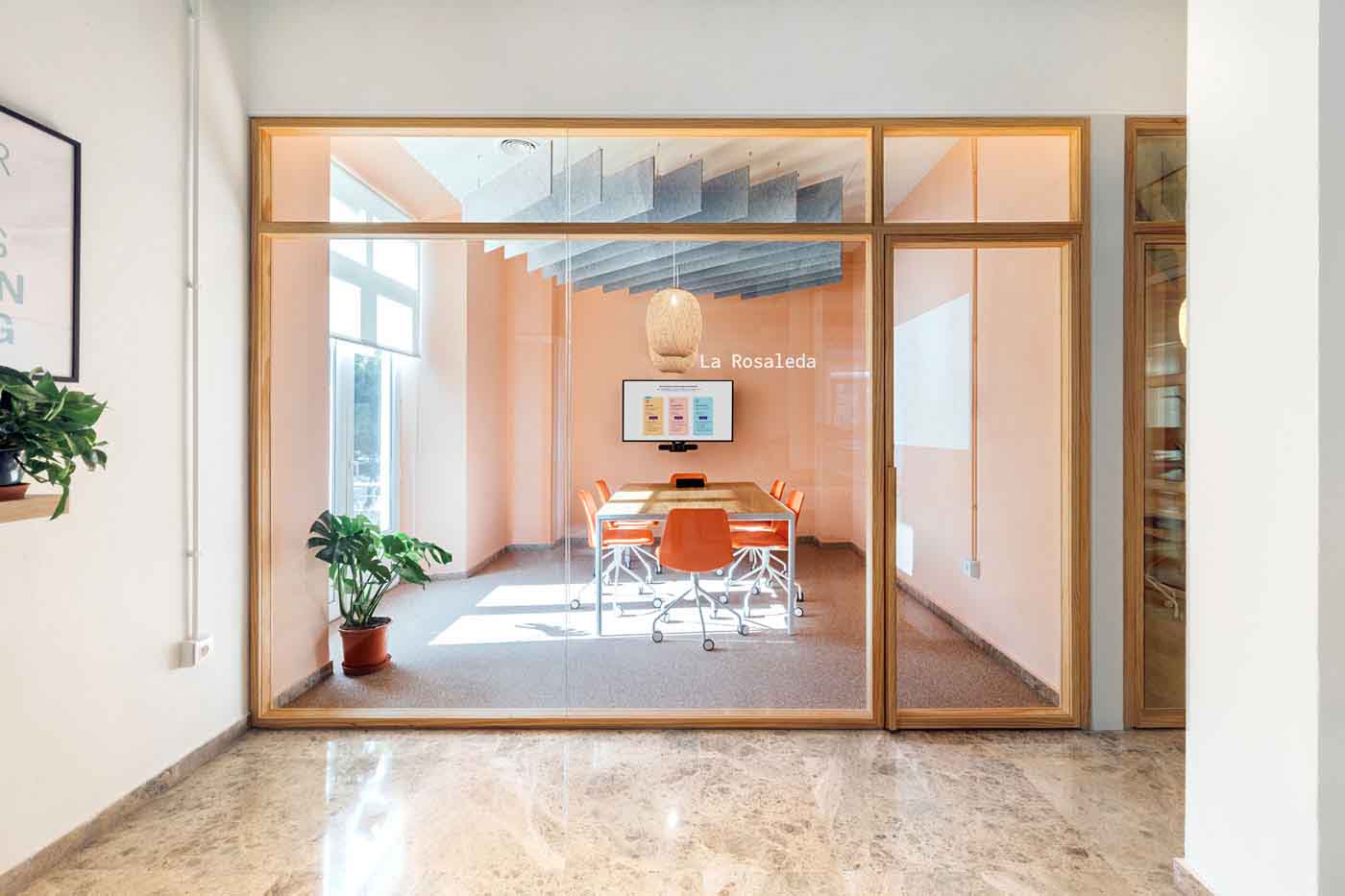 Sala de reuniones con cerramiento acristalado de madera y suelo de mármol en las oficinas de Plytix