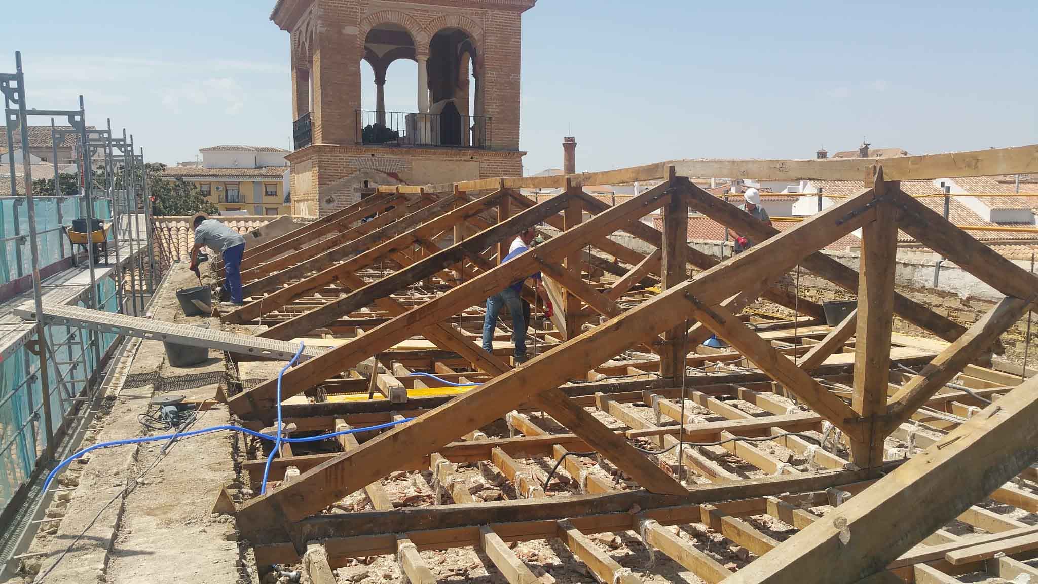 Operarios trabajando sobre la antigua estructura de madera de la cubierta de la casa palacio