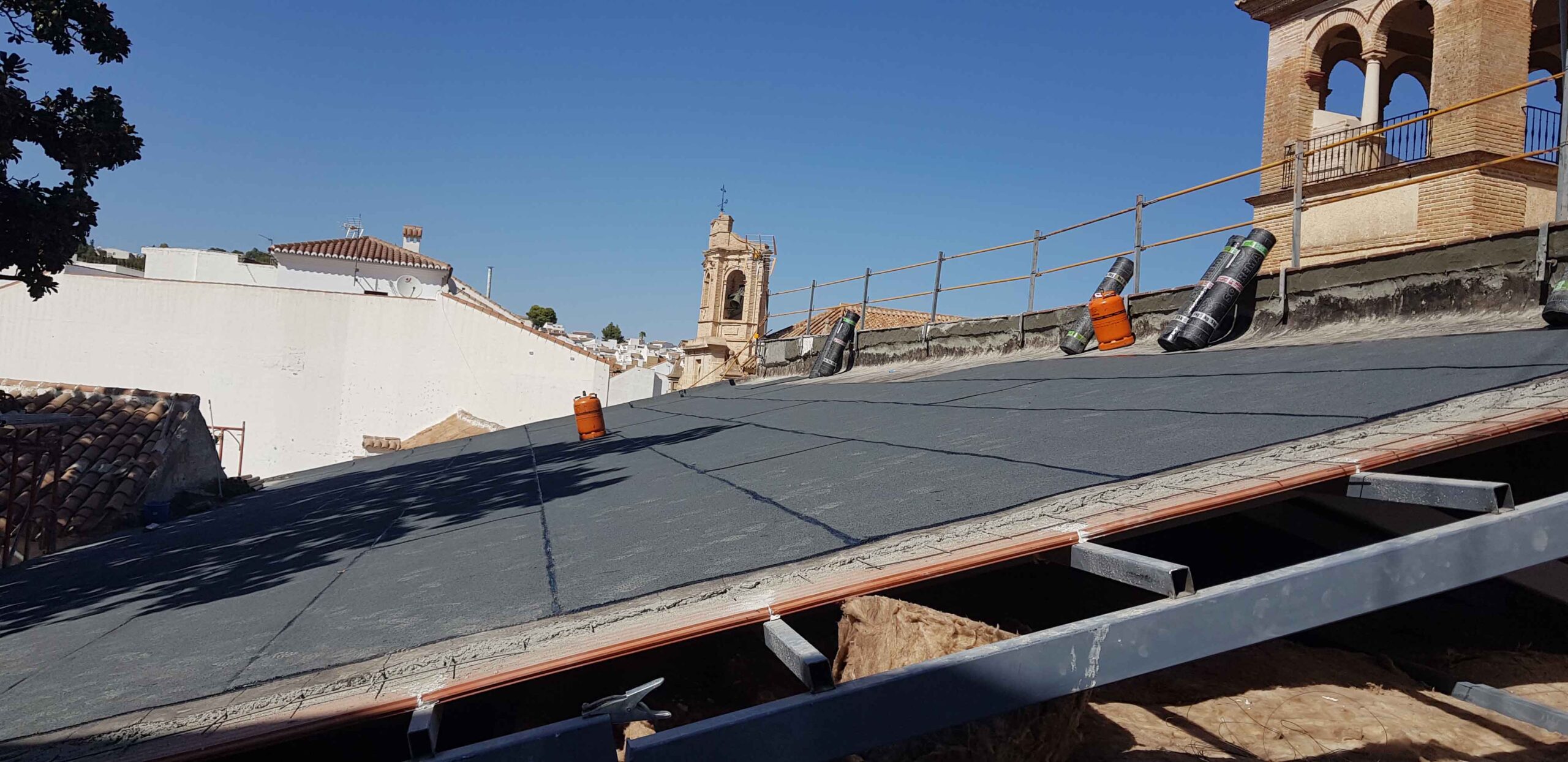 Cubierta inclinada con panel aislante y espadaaña al fondo en el colegio histórico