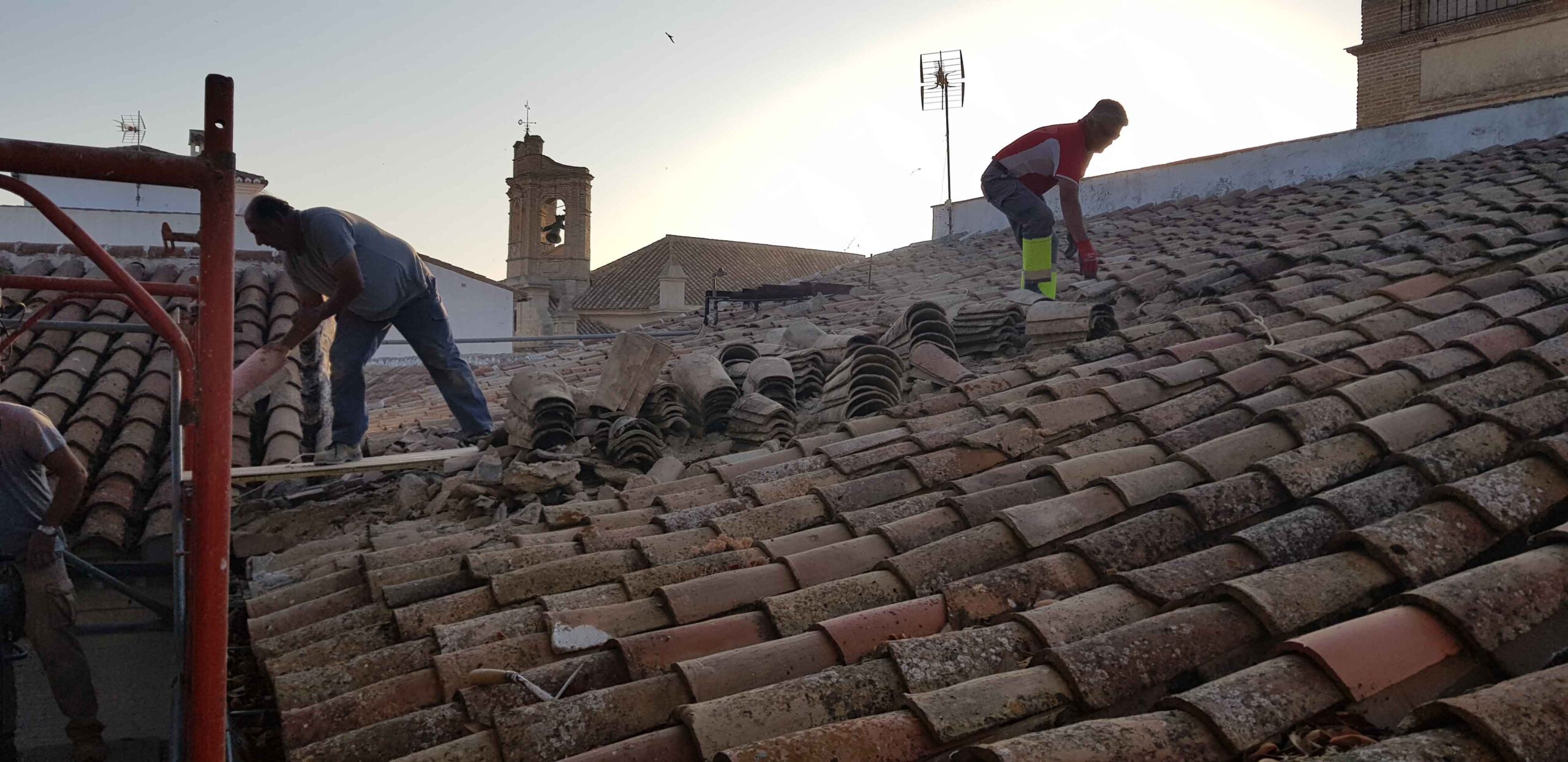Operarios colocando teja cerámica sobre la cubierta del colegio histórico