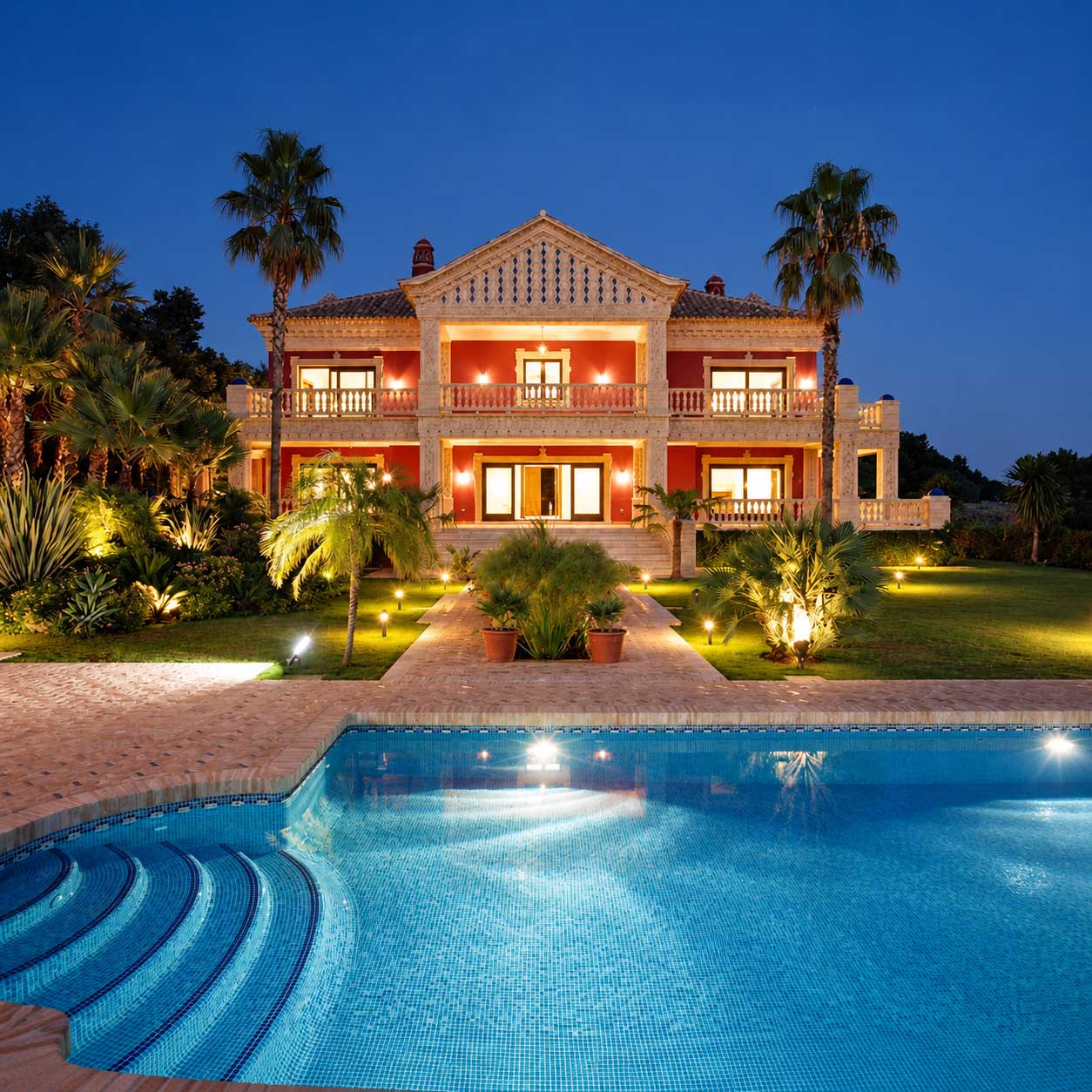 Piscina con escalones y villa iluminada al atardecer en Marbella