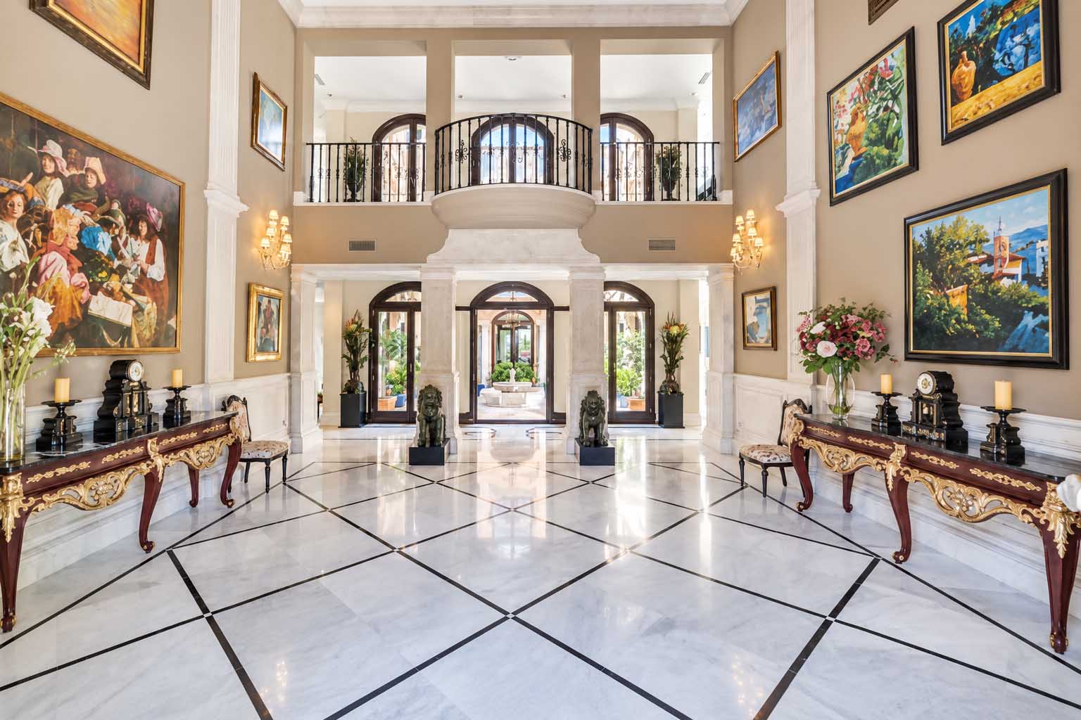 Hall con suelo de mármol, doble altura y balconada interior en la Villa Alhambra