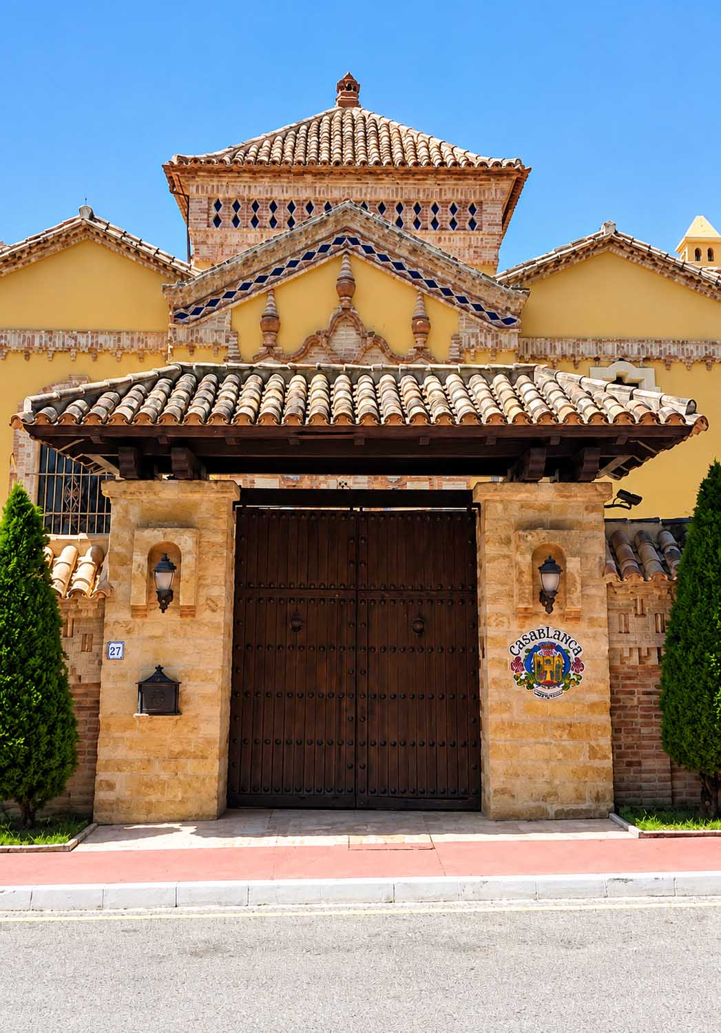 Portón de madera en la portada de ladrillo y teja de la Villa Casa Blanca en Marbella