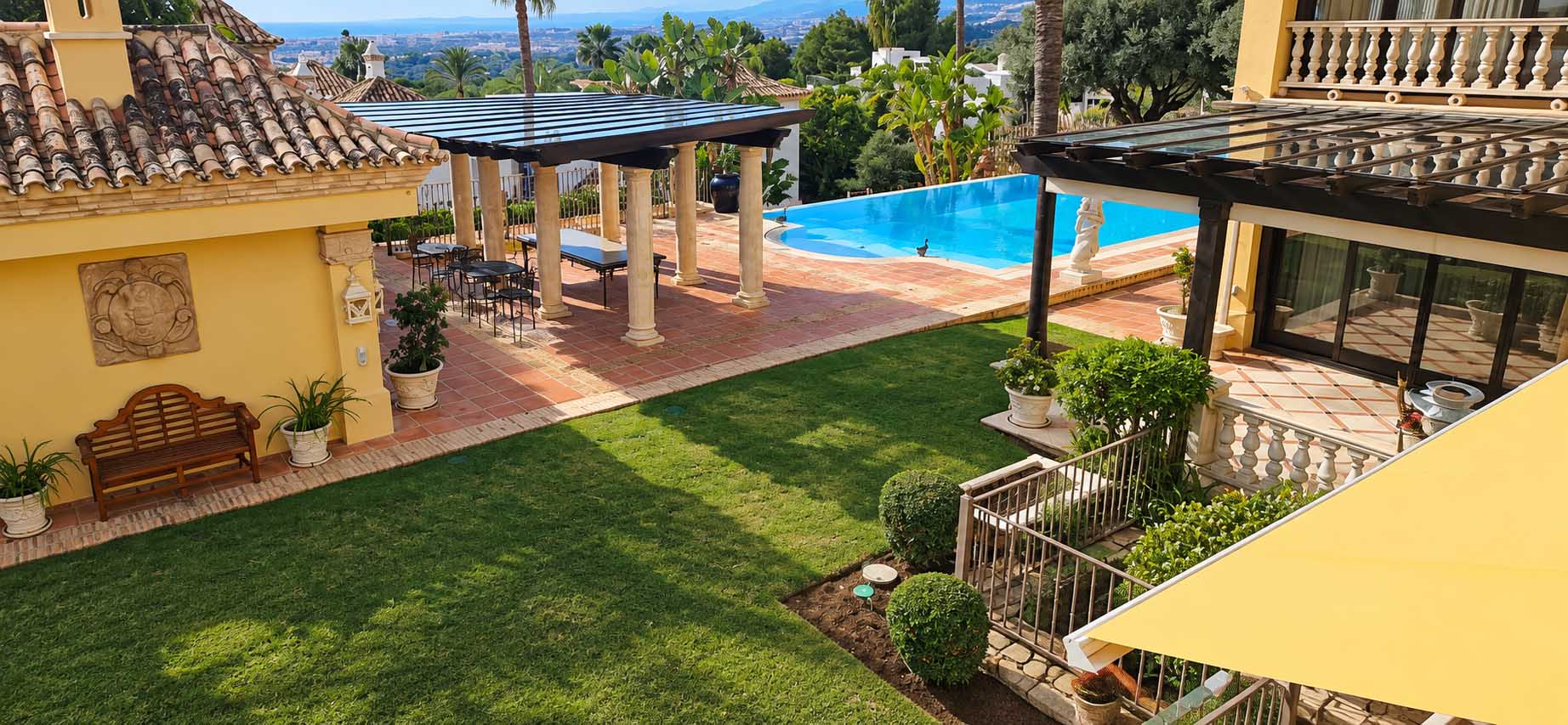 Terraza y pérgola con piscina al fondo en el jardín de la Villa Casa Blanca