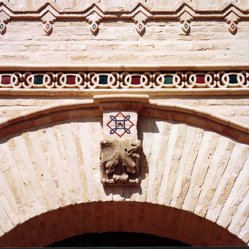 Detalle de arco de ladrillo con escudo ornamental y cornisa decorada