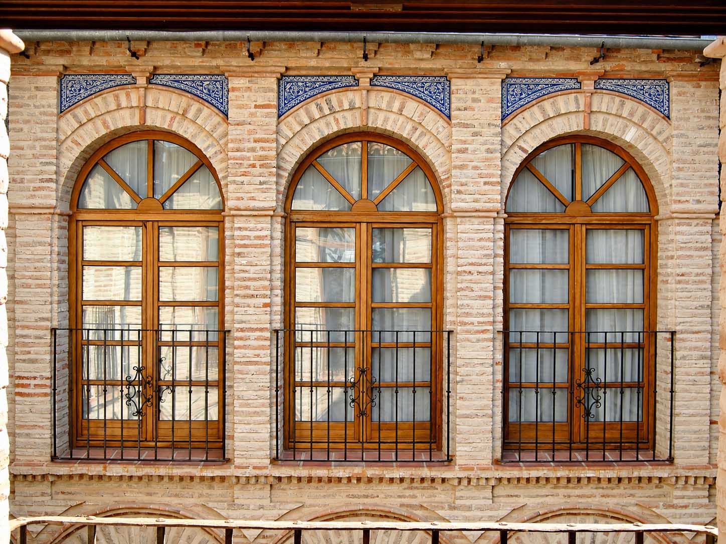 Galería de ventanales con arcos de ladrillo y carpintería de madera