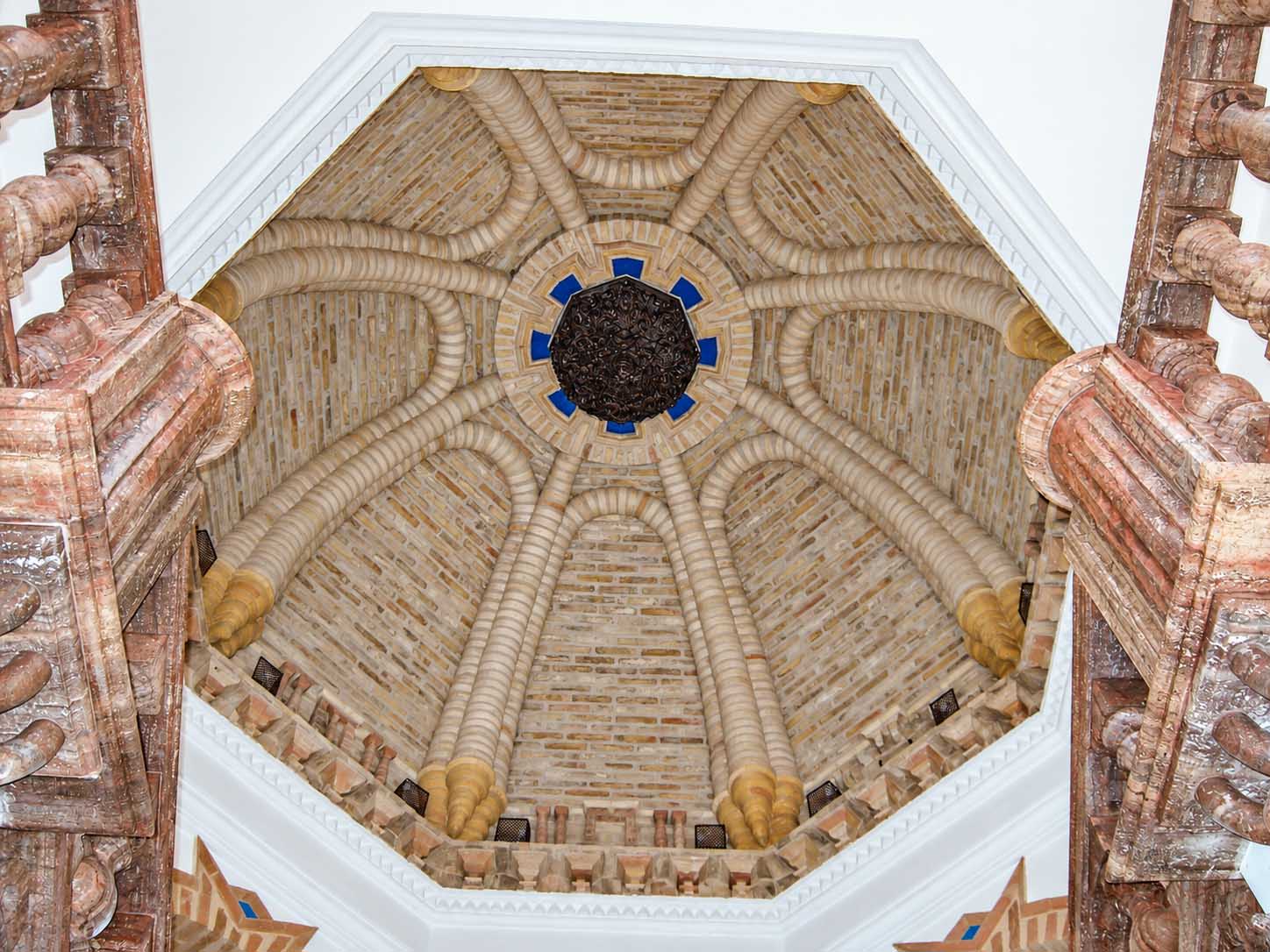 Cúpula de ladrillo con rosetón central azul y barandilla de madera tallada
