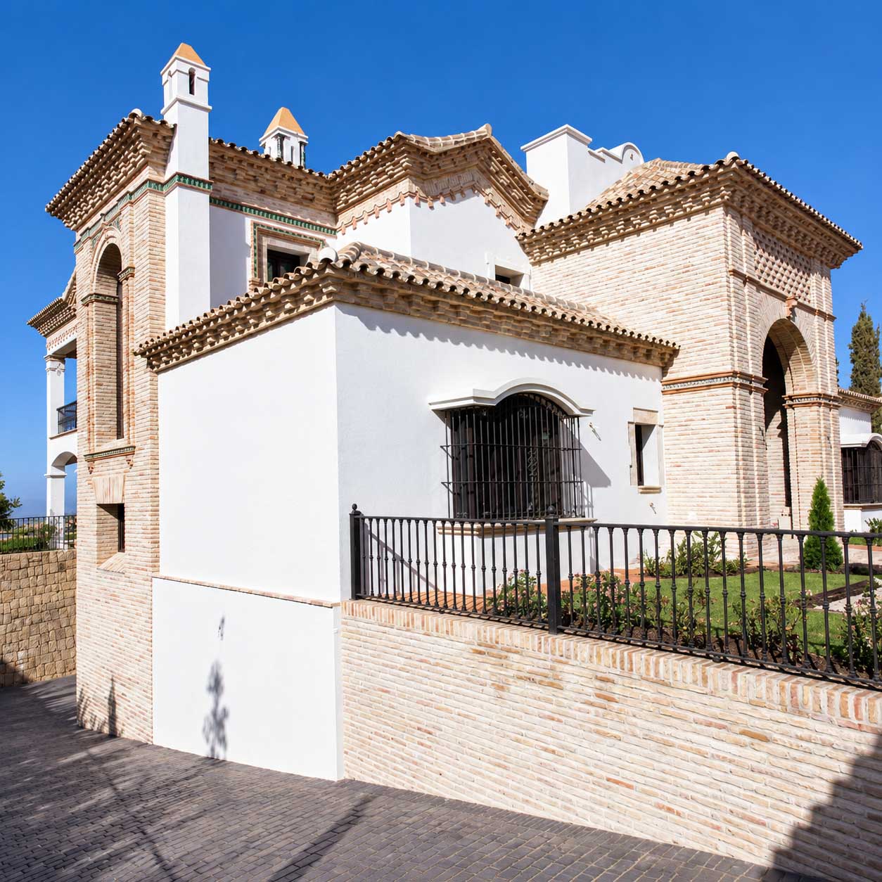 Villa blanca con arcos, cubiertas de teja y terraza elevada en la Costa del Sol